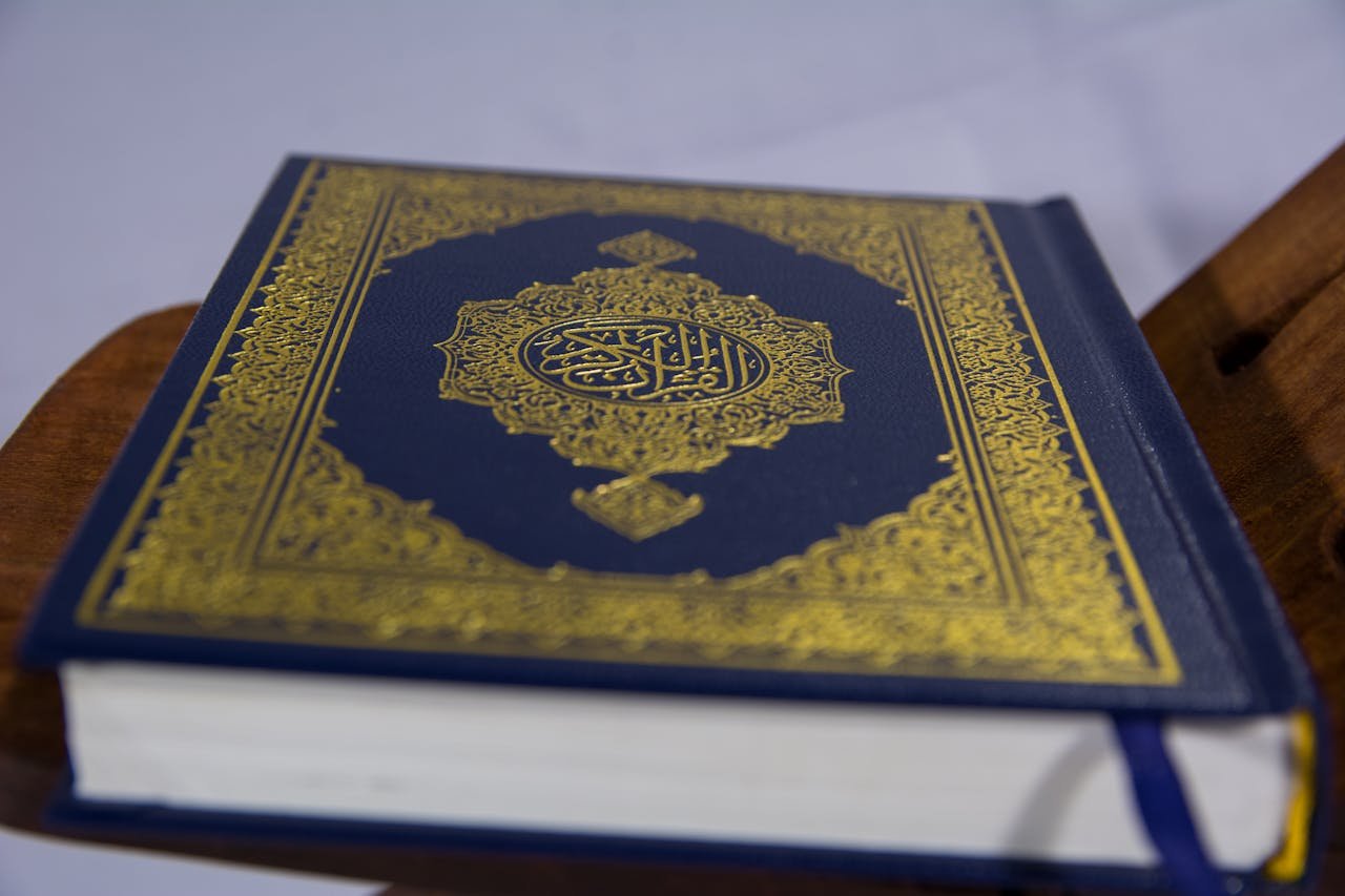 Close-up of Quran on stand, showcasing intricate Arabic calligraphy design.